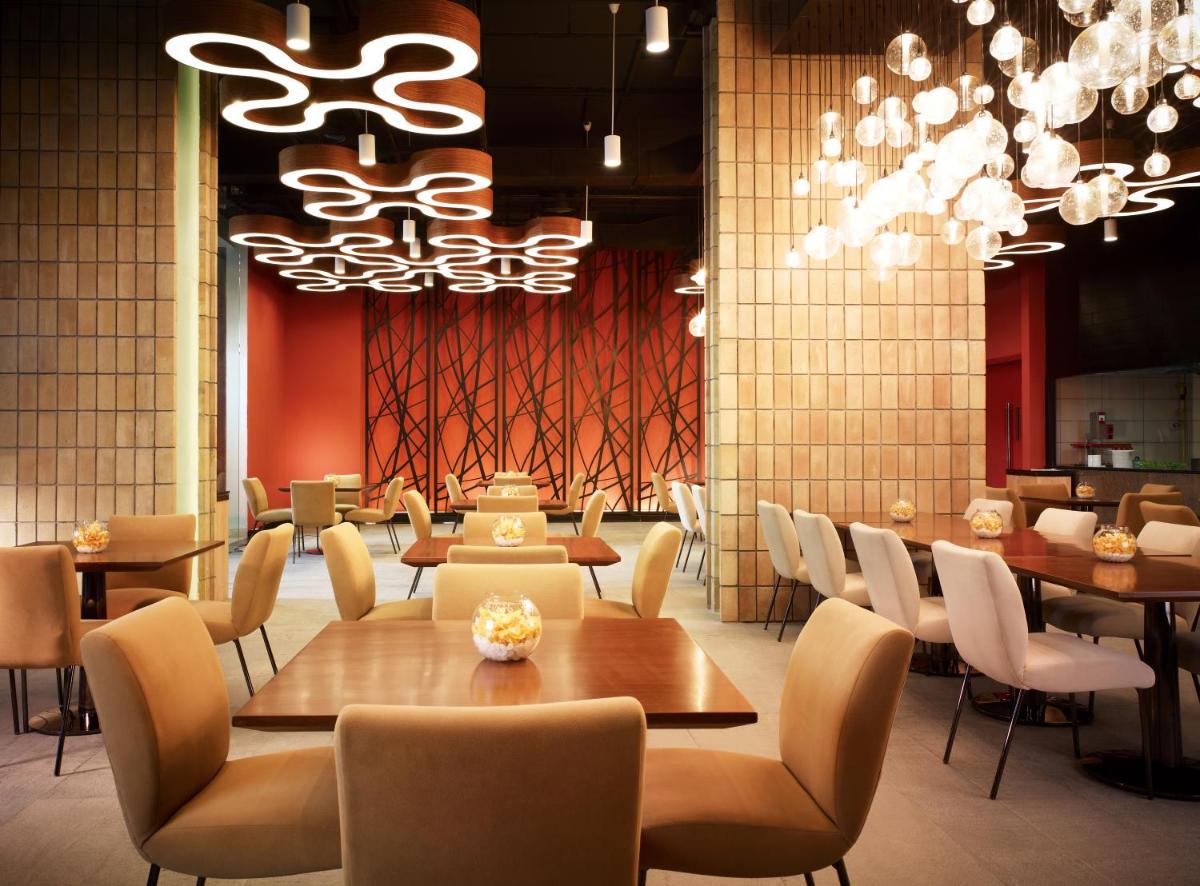 a dining room with tables and chairs and chandeliers at Taj Yeshwantpur Bengaluru in Bengaluru a dining room with tables and chairs and chandeliers at Taj Yeshwantpur Bengaluru in Bengaluru