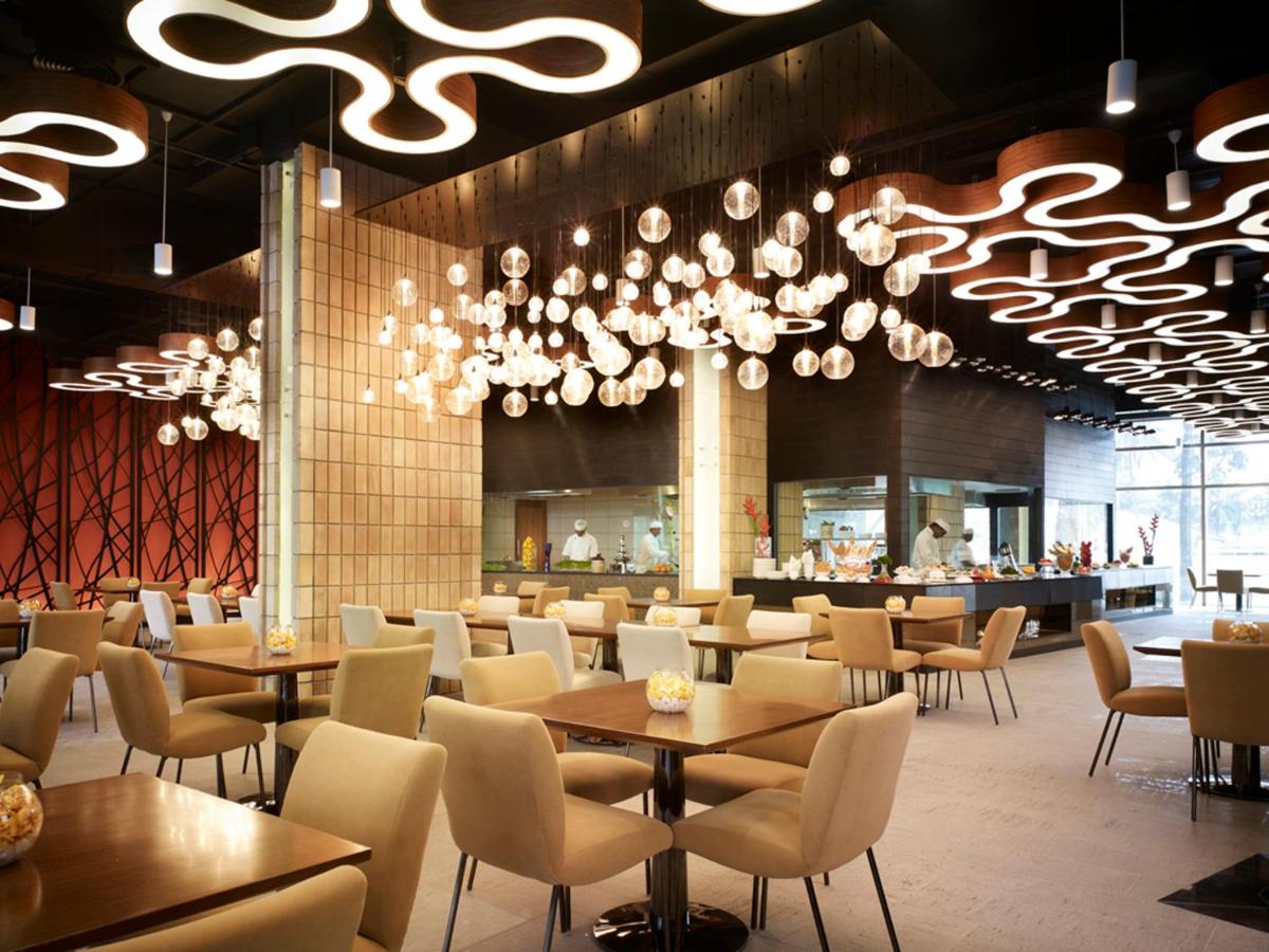 a restaurant with tables and chairs and a chandelier at Taj Yeshwantpur Bengaluru in Bengaluru a restaurant with tables and chairs and a chandelier at Taj Yeshwantpur Bengaluru in Bengaluru