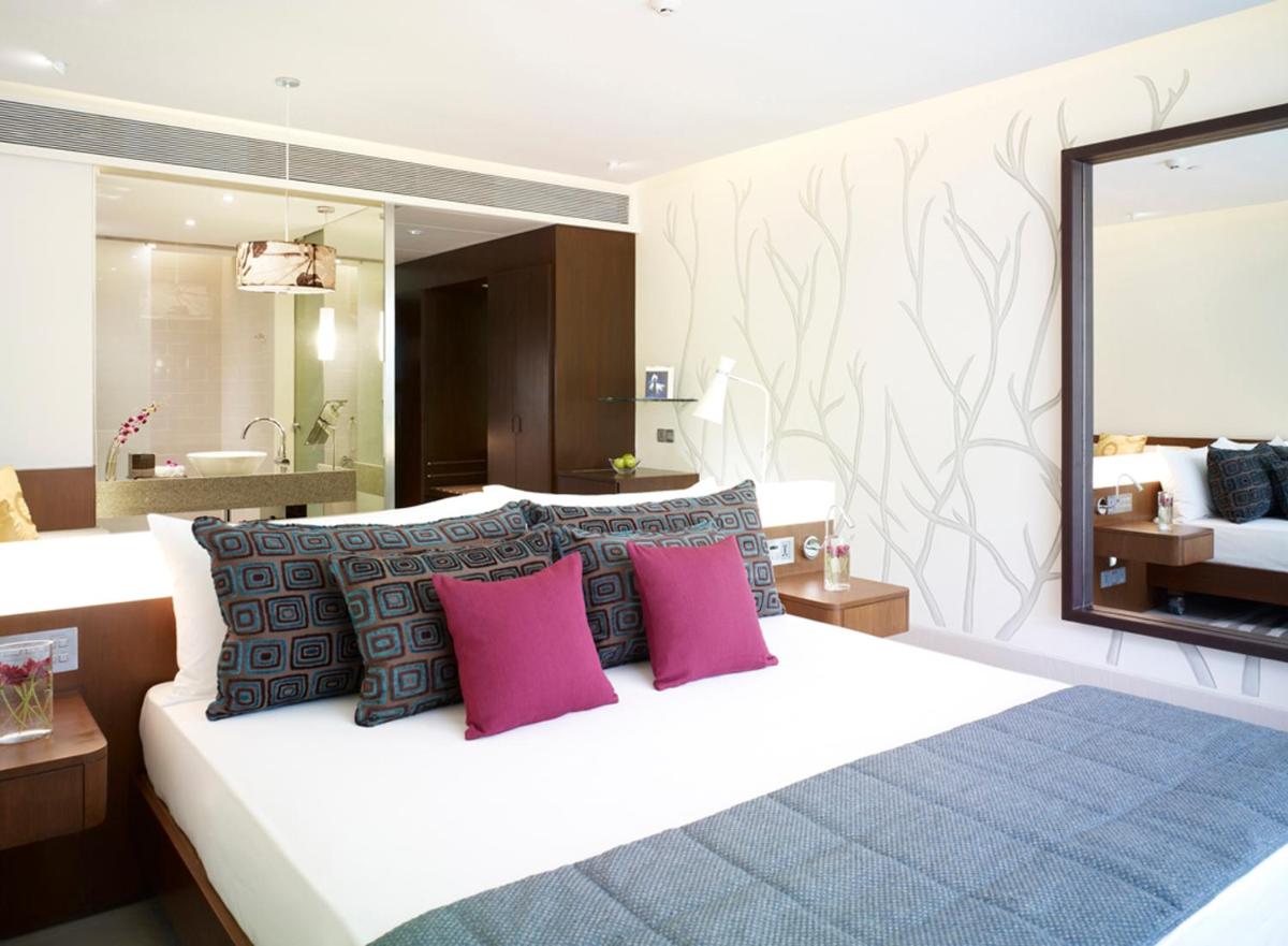 a bedroom with a large bed with pink pillows at Taj Yeshwantpur Bengaluru in Bengaluru a bedroom with a large bed with pink pillows at Taj Yeshwantpur Bengaluru in Bengaluru