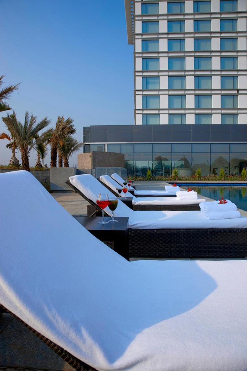 a row of beds on a resort with a building at Taj Yeshwantpur Bengaluru in Bengaluru a row of beds on a resort with a building at Taj Yeshwantpur Bengaluru in Bengaluru