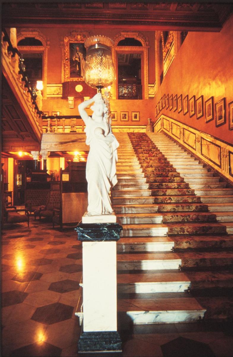 a statue of a woman on a pedestal in a staircase at Taj Falaknuma Palace in Hyderabad