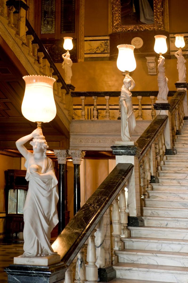 two statues of women on stairs with lights at Taj Falaknuma Palace in Hyderabad