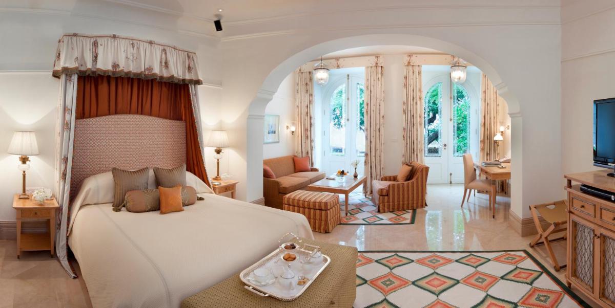 a bedroom with a large bed and a living room at Taj Falaknuma Palace in Hyderabad