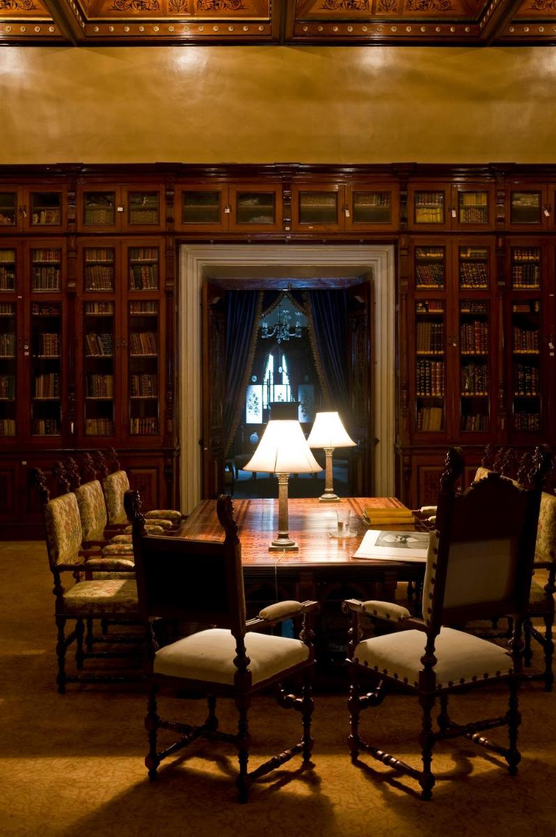 a library with a table with chairs and a lamp at Taj Falaknuma Palace in Hyderabad
