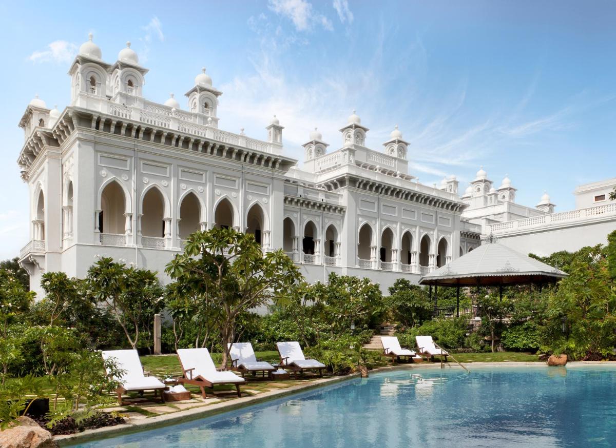 a large white building with lounge chairs and a swimming pool at Taj Falaknuma Palace in Hyderabad a large white building with lounge chairs and a swimming pool at Taj Falaknuma Palace in Hyderabad