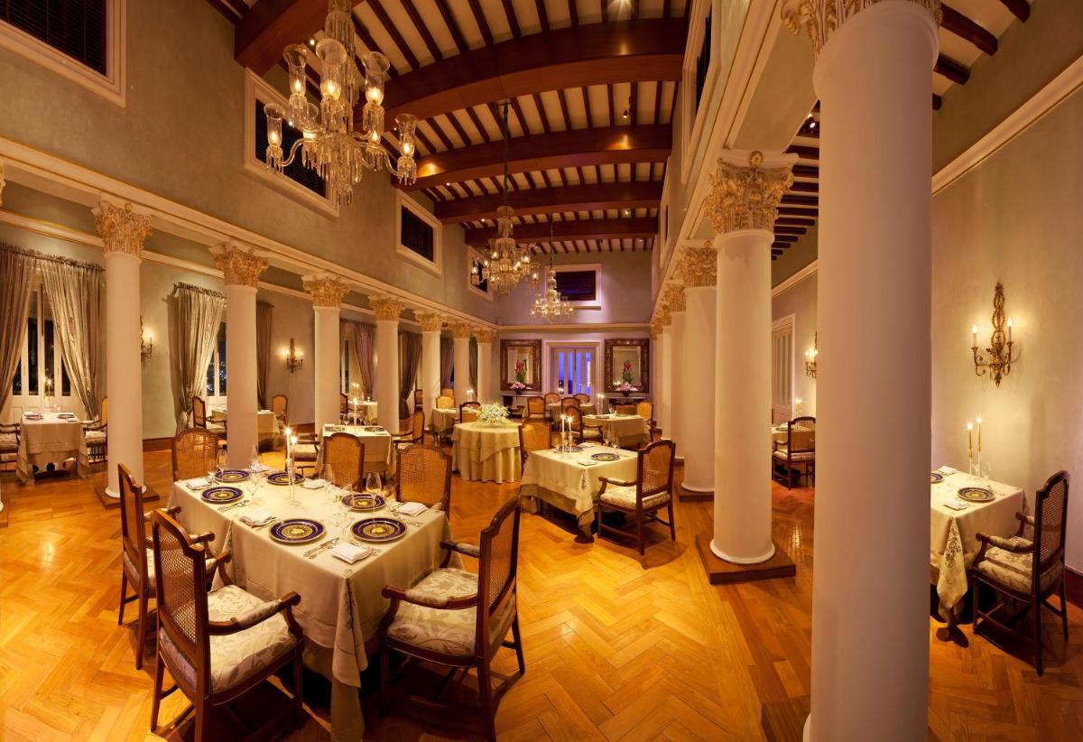 a dining room with tables and chairs and a chandelier at Taj Falaknuma Palace in Hyderabad