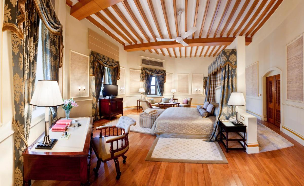 a bedroom with a bed and a desk in a room at Taj Falaknuma Palace in Hyderabad