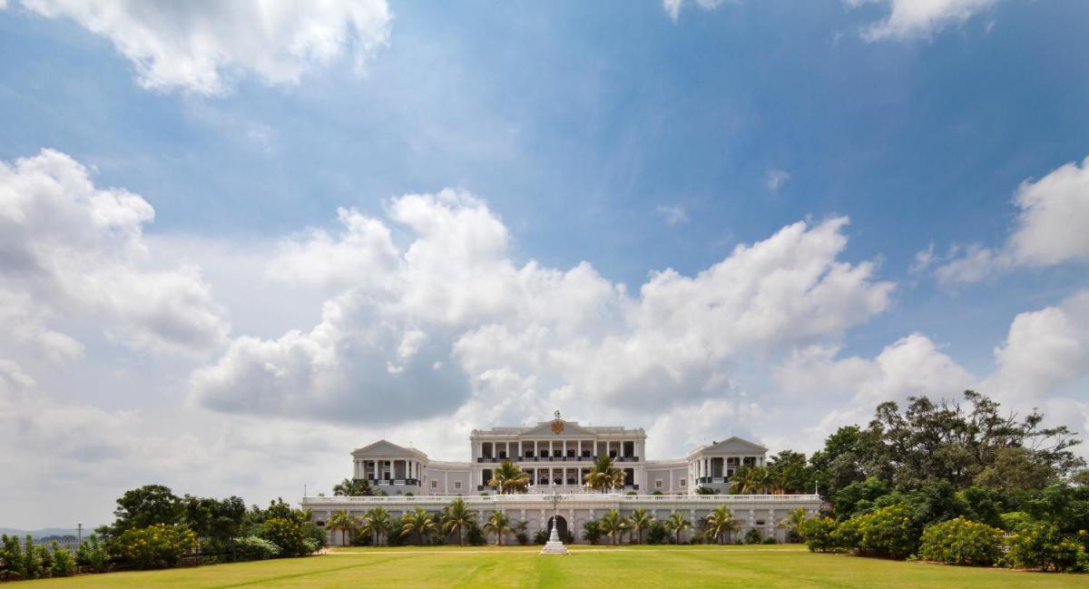 a large white building on a field with a cloudy sky at Taj Falaknuma Palace in Hyderabad