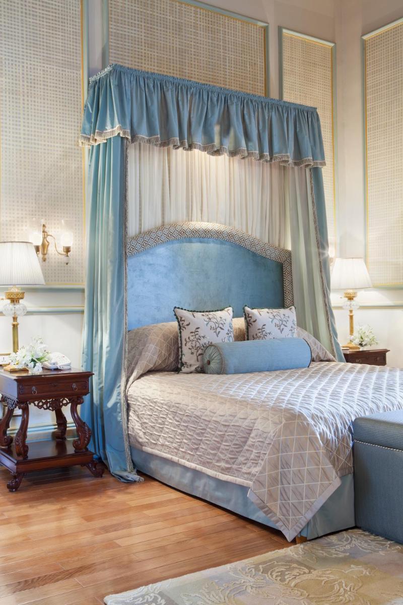 a bedroom with a bed with a blue canopy at Taj Falaknuma Palace in Hyderabad