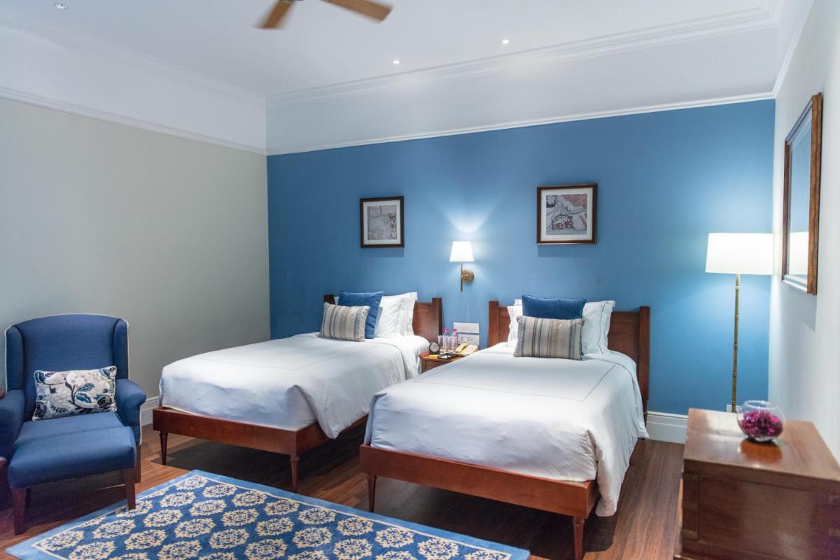 a room with two beds and a blue wall at Taj Connemara, Chennai in Chennai