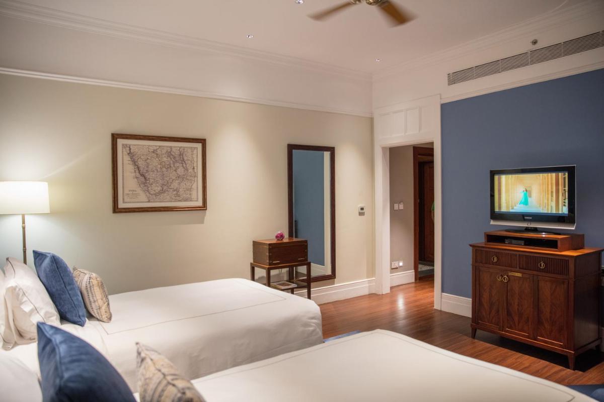 a hotel room with two beds and a flat screen tv at Taj Connemara, Chennai in Chennai
