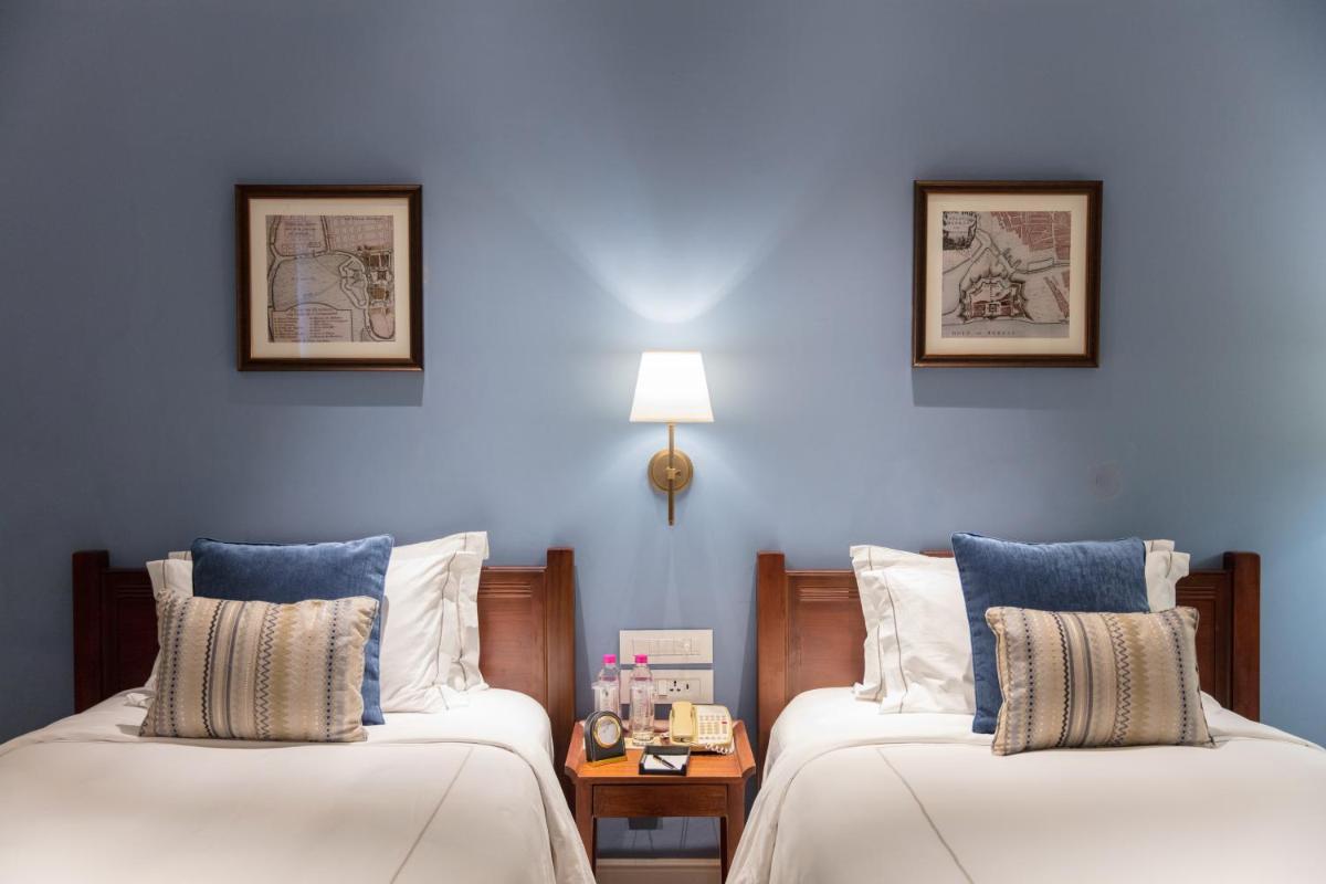 two beds in a room with blue walls at Taj Connemara, Chennai in Chennai