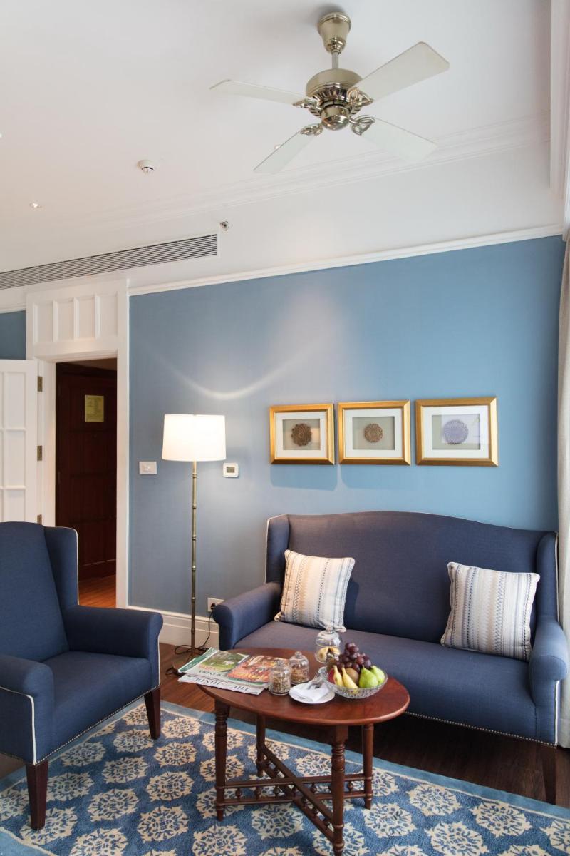 a living room with two blue couches and a table at Taj Connemara, Chennai in Chennai