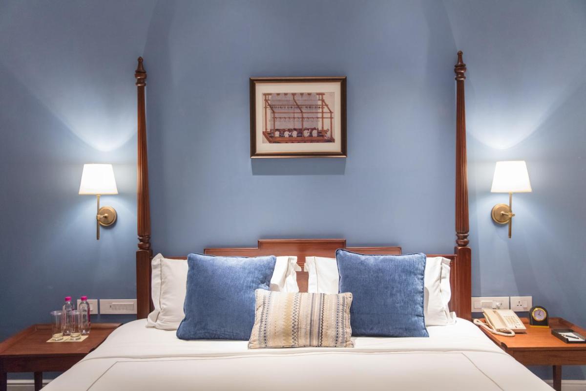 a bedroom with blue walls and a bed with blue pillows at Taj Connemara, Chennai in Chennai