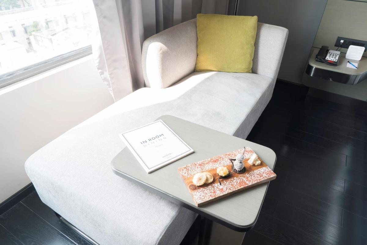 a living room with a white couch and a table at Novotel Chennai Chamiers Road in Chennai