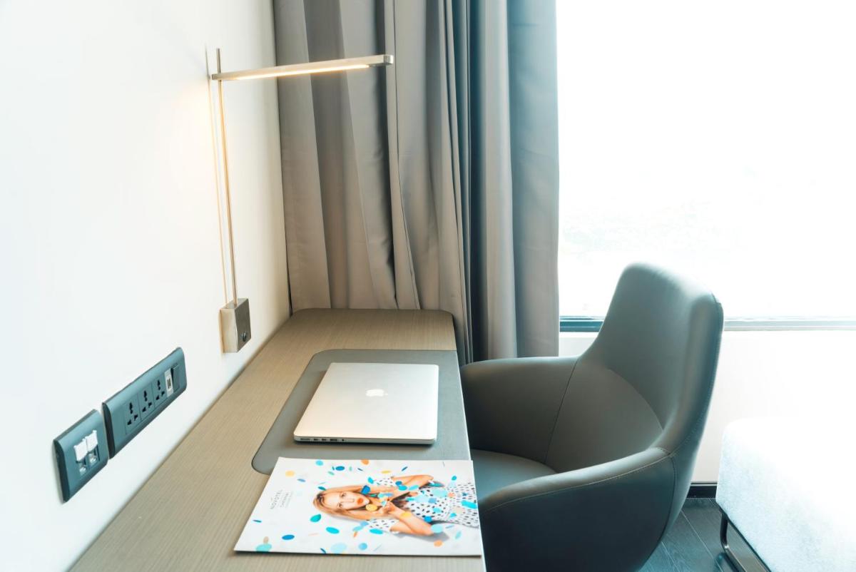 a room with a desk with a laptop and a chair at Novotel Chennai Chamiers Road in Chennai