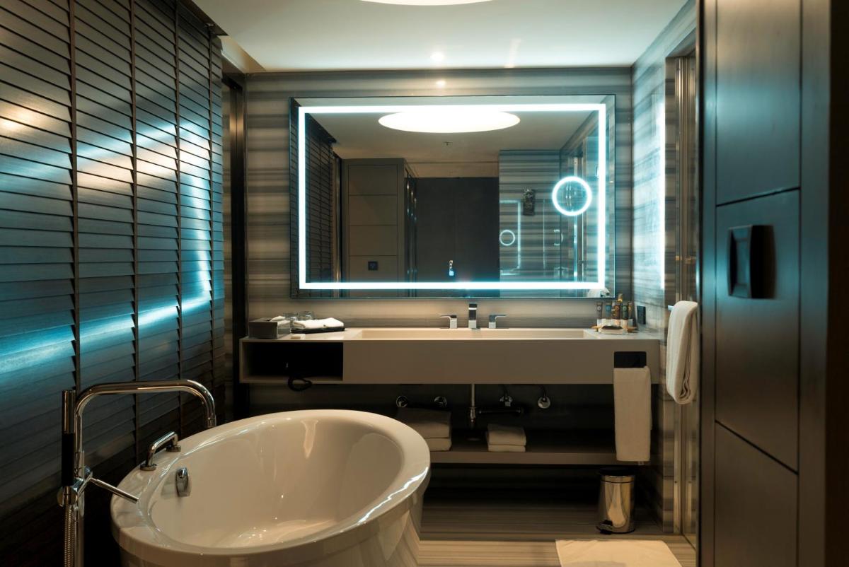 a bathroom with a tub and a sink and a mirror at Novotel Chennai Chamiers Road in Chennai