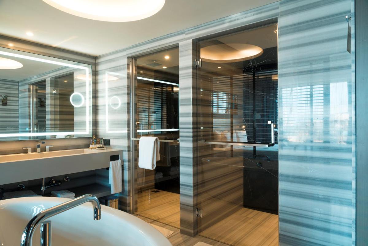 a bathroom with a tub and a glass shower at Novotel Chennai Chamiers Road in Chennai