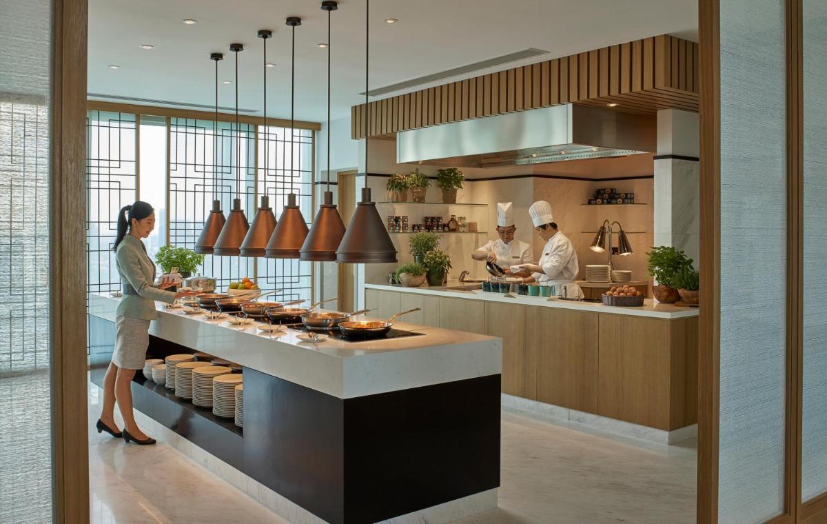 a kitchen with three chefs preparing food in a kitchen at Shangri-La Singapore in Singapore