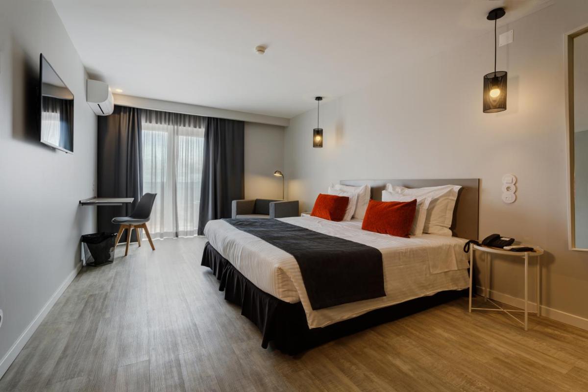 um quarto de hotel com uma cama grande com travesseiros vermelhos em Sport Hotel Gym + SPA na Covilhã