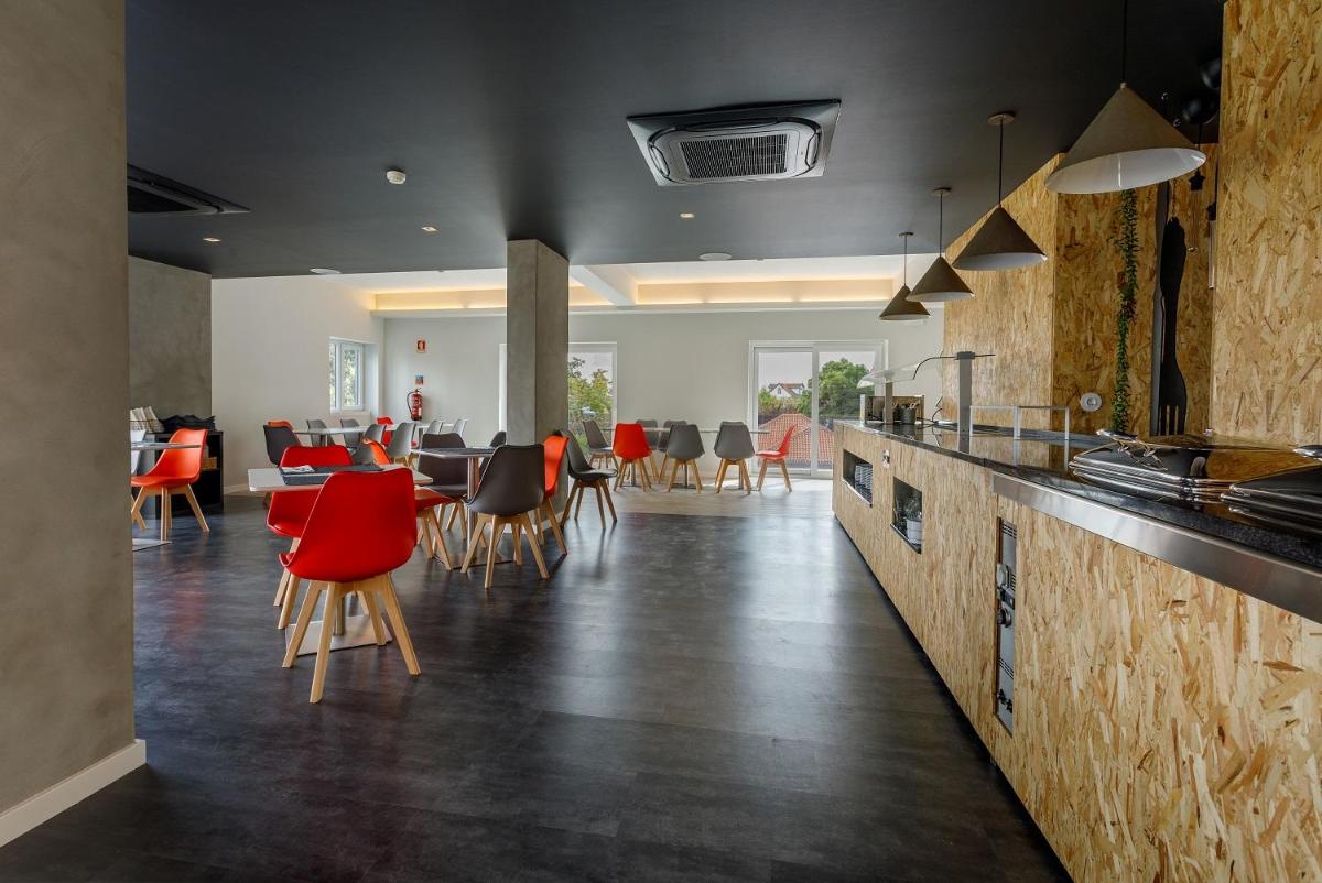 uma cozinha com cadeiras vermelhas e uma sala de jantar em Sport Hotel Gym + SPA na Covilhã