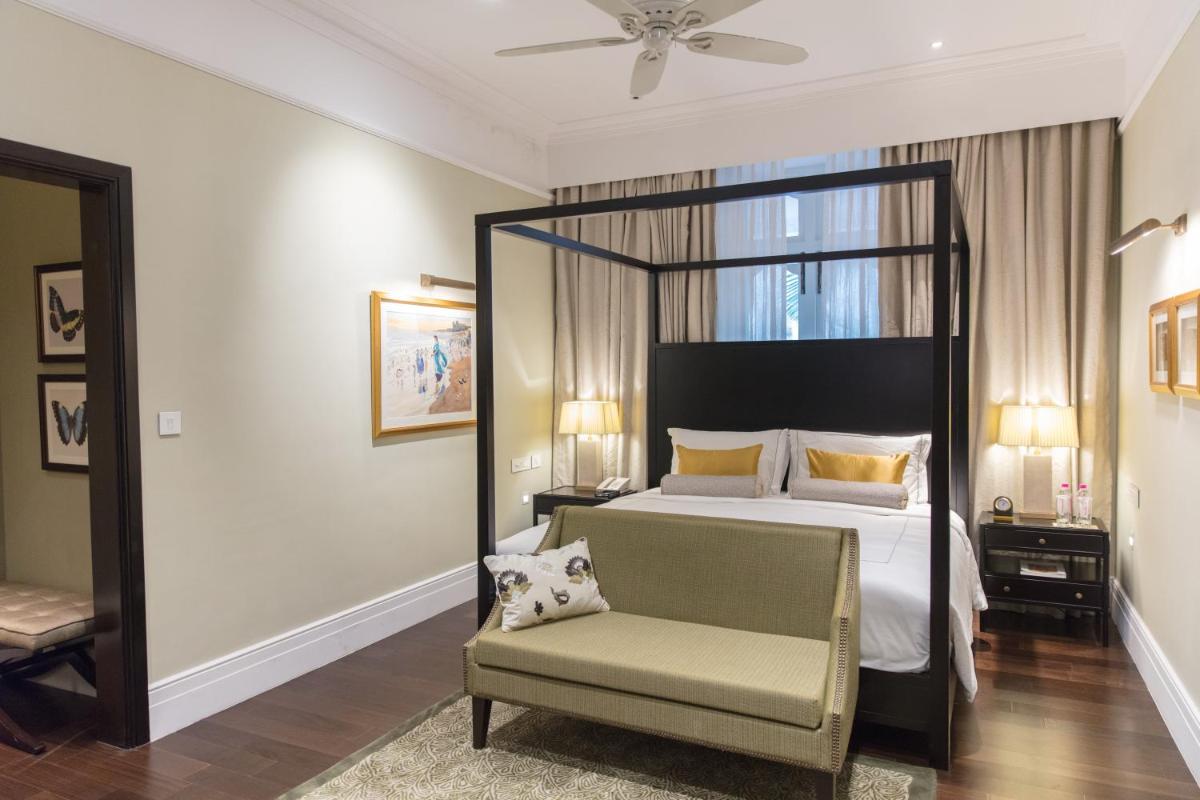 a bedroom with a canopy bed and a chair at Taj Connemara, Chennai in Chennai