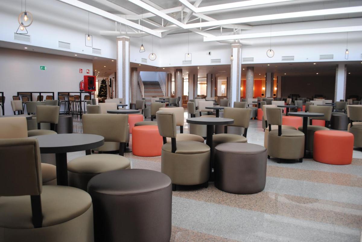 Una cafetería con mesas y taburetes en un edificio. en Gara Suites Golf & Spa, en Playa de las Américas