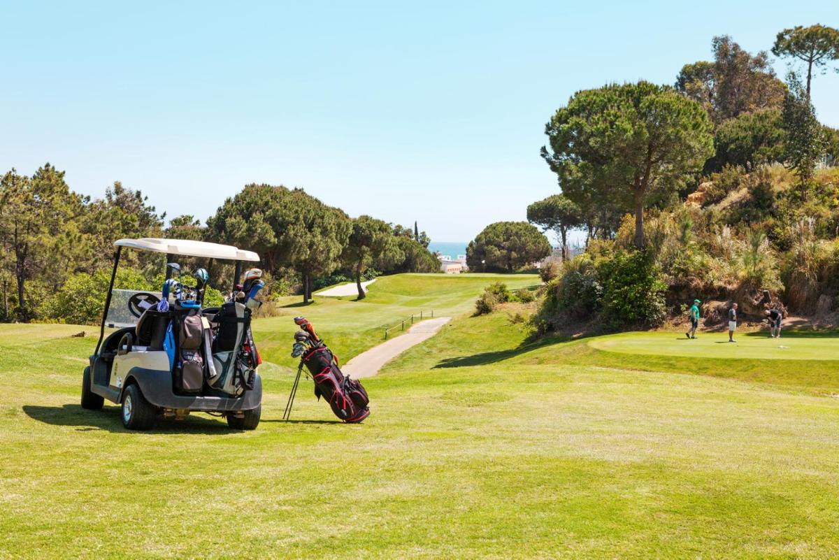 un carro de golf estacionado en un campo de golf en Ama Islantilla Resort, en Islantilla