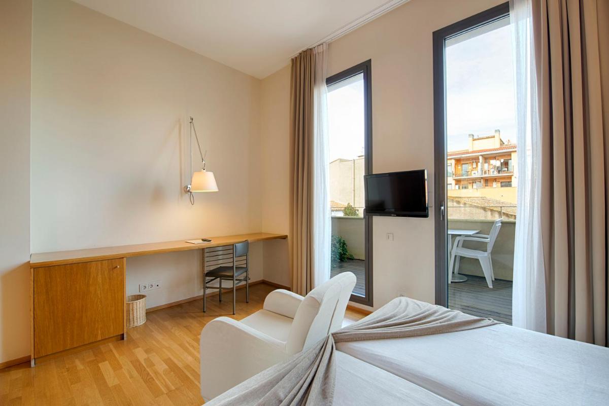 Una habitación de hotel con una cama, un escritorio y un balcón. en Hotel Balneario Prats, en Caldes de Malavella