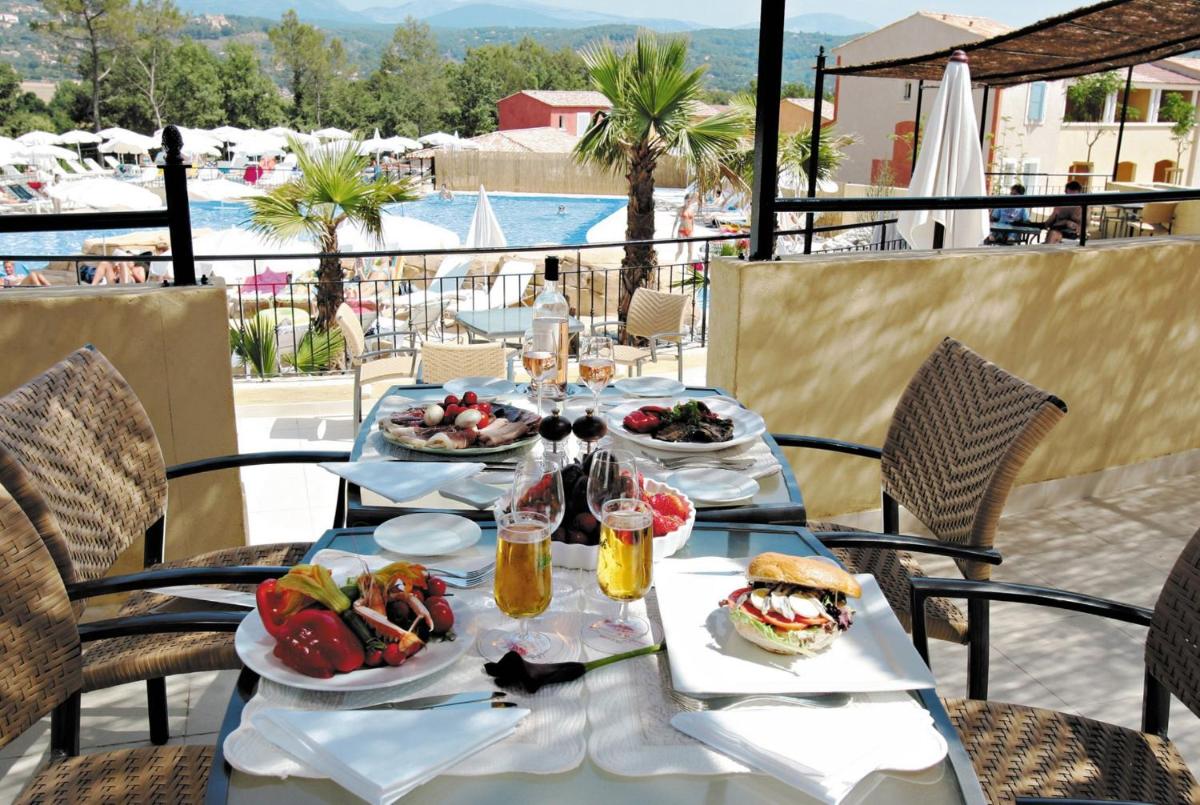 - une table avec des assiettes de nourriture et des boissons sur la terrasse dans l'établissement Lagrange Vacances Domaine de Fayence, à Fayence