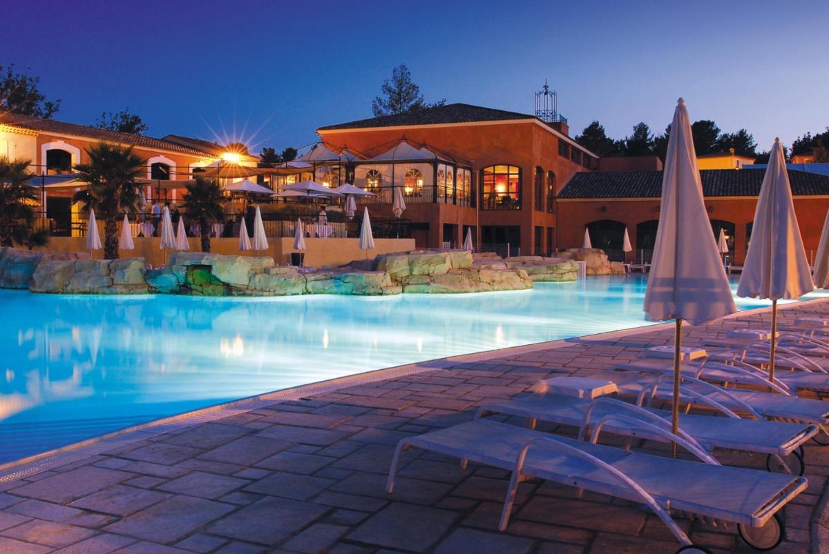 une piscine avec chaises et parasols dans un complexe hôtelier dans l'établissement Lagrange Vacances Domaine de Fayence, à Fayence