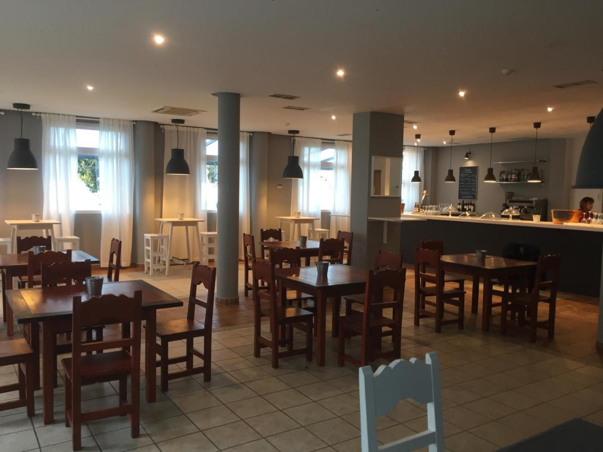 Un restaurante con mesas y sillas de madera y una cocina. en Hotel Balneario De Alceda, en Alceda 34 fotos más
