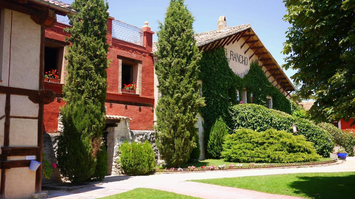 un edificio de ladrillo rojo con árboles delante de él en Hotel El Rancho, en Segovia