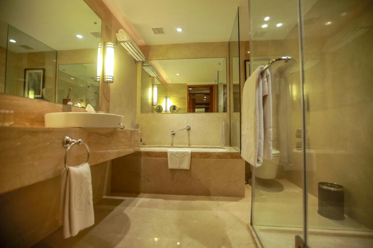 a bathroom with a shower and a sink and a tub at Taj Coromandel in Chennai