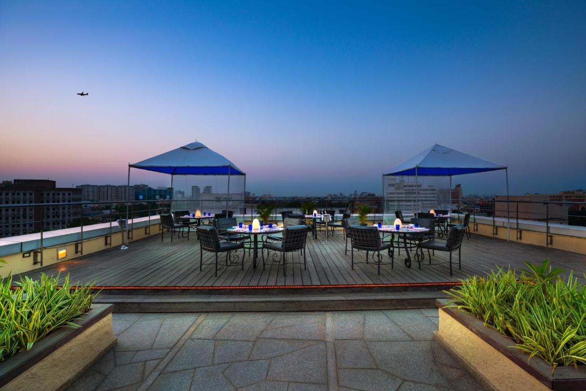 a deck with tables and chairs on a roof at Taj Club House in Chennai