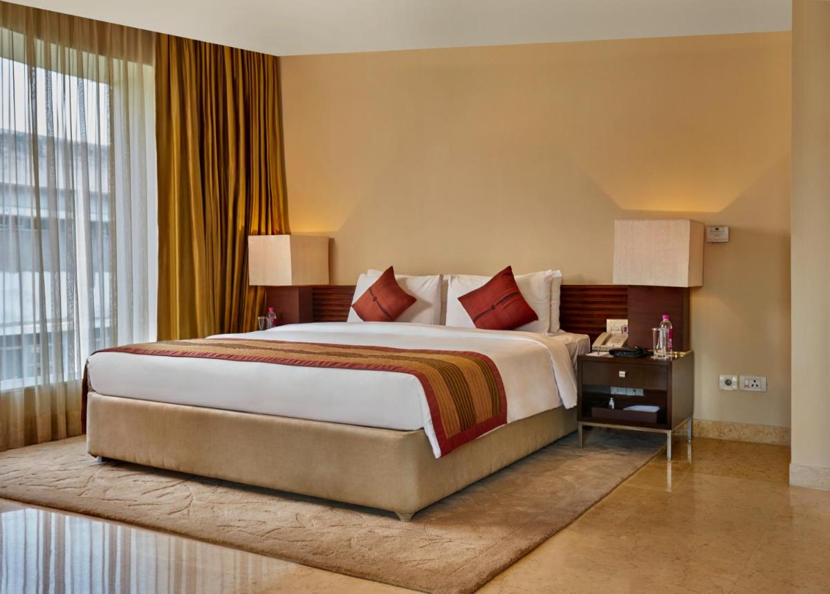 a bedroom with a large bed and a large window at Taj Club House in Chennai