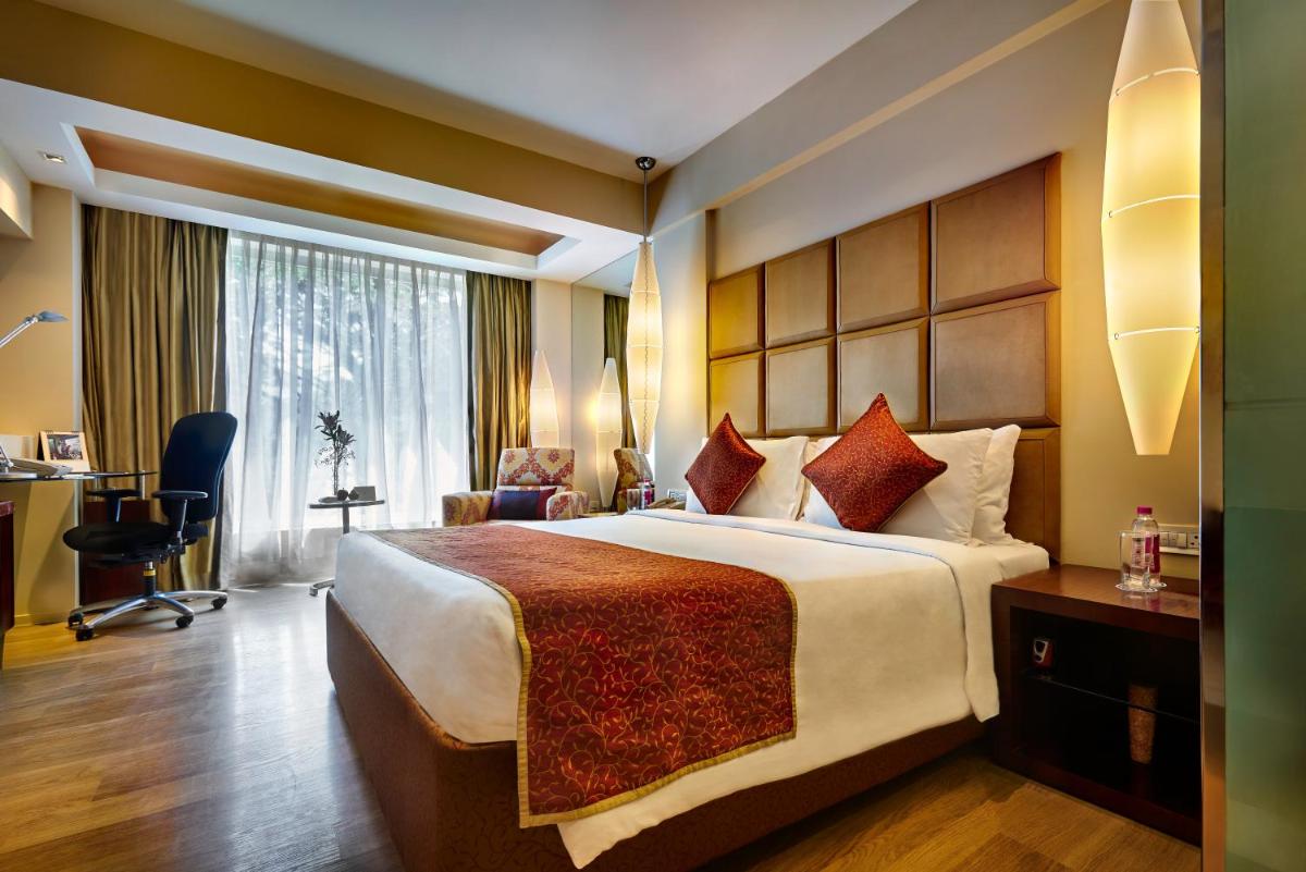 a hotel room with a large bed and a desk at Taj Club House in Chennai