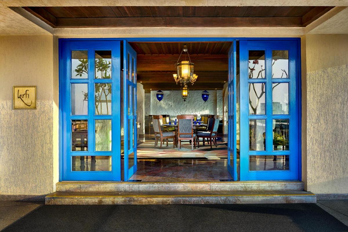 an entrance to a house with blue doors and a dining room at Taj Club House in Chennai