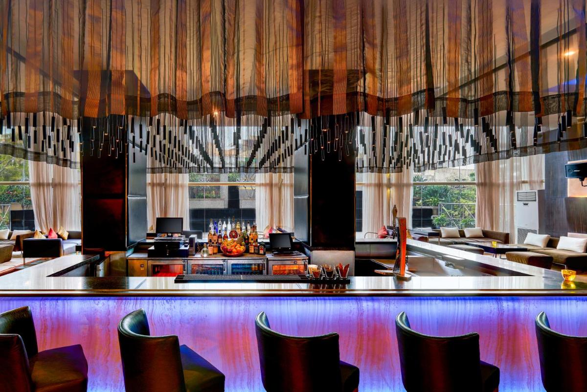 a lobby with chairs and a bar with curtains at Taj Club House in Chennai