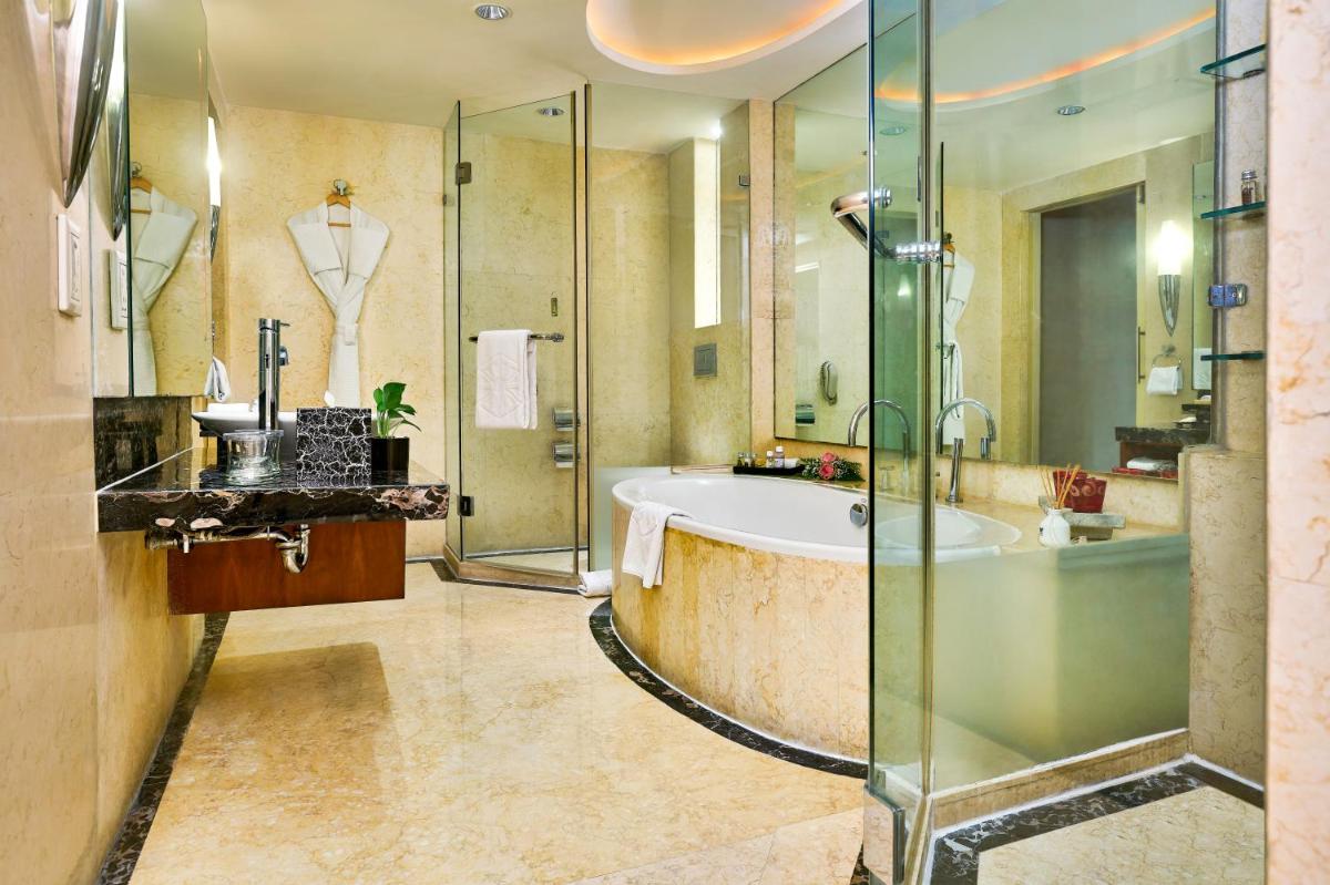 a bathroom with a tub and a shower and a sink at Taj Club House in Chennai a bathroom with a tub and a shower and a sink at Taj Club House in Chennai