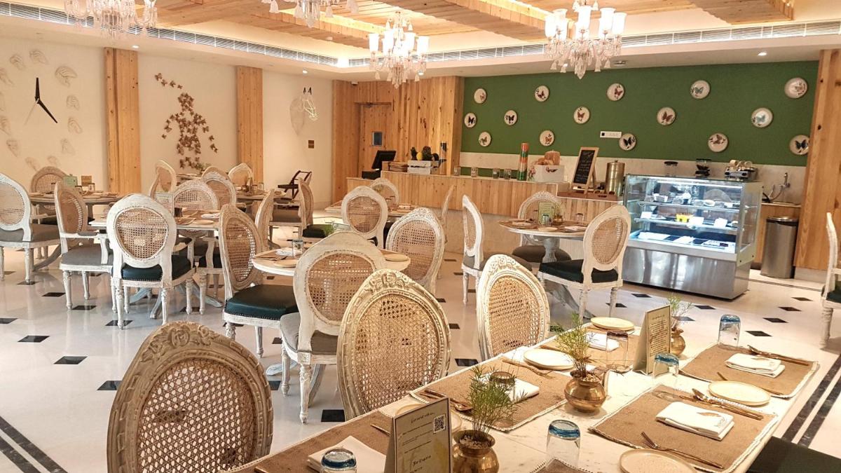 a dining room with tables and chairs and chandeliers at Ramada by Wyndham Lucknow Hotel and Convention Center in Lucknow