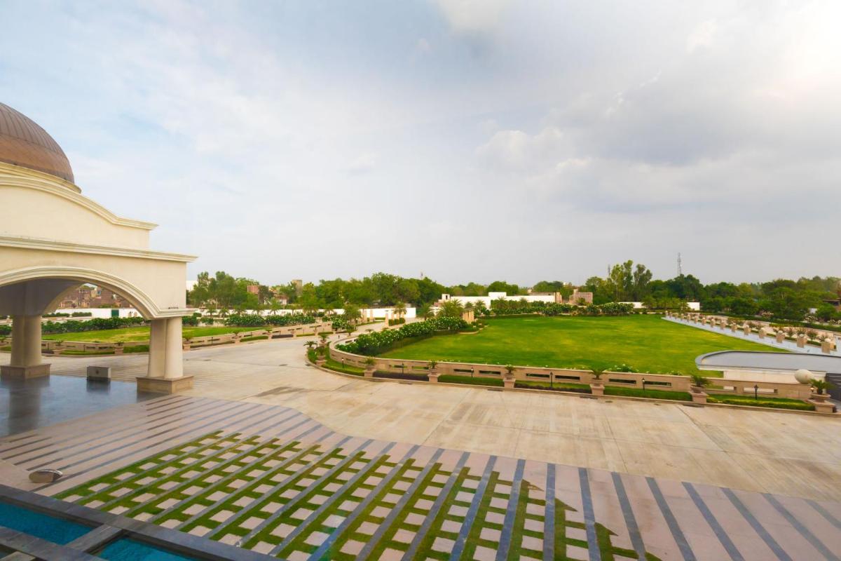 a view of a park with benches and a building at Ramada by Wyndham Lucknow Hotel and Convention Center in Lucknow