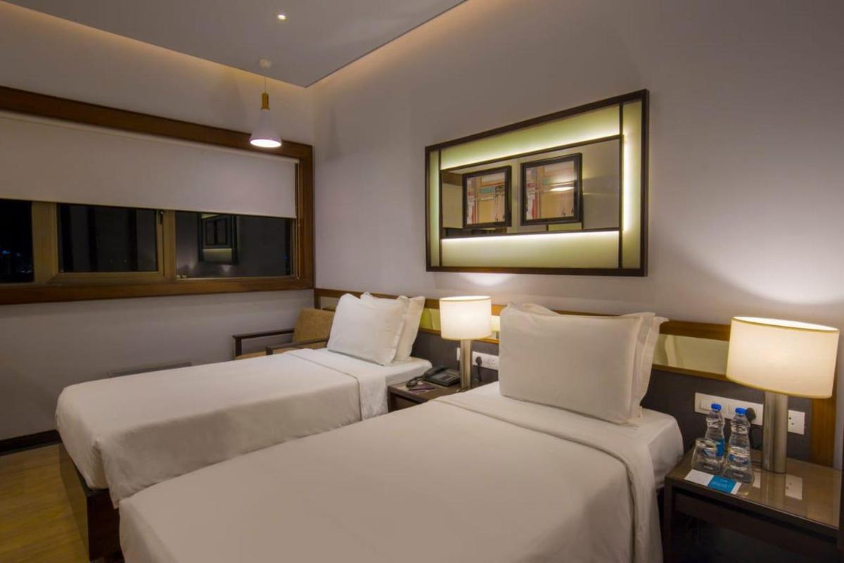 a hotel room with two beds and a mirror at Zone By The Park Kolkata, Newtown in Kolkata