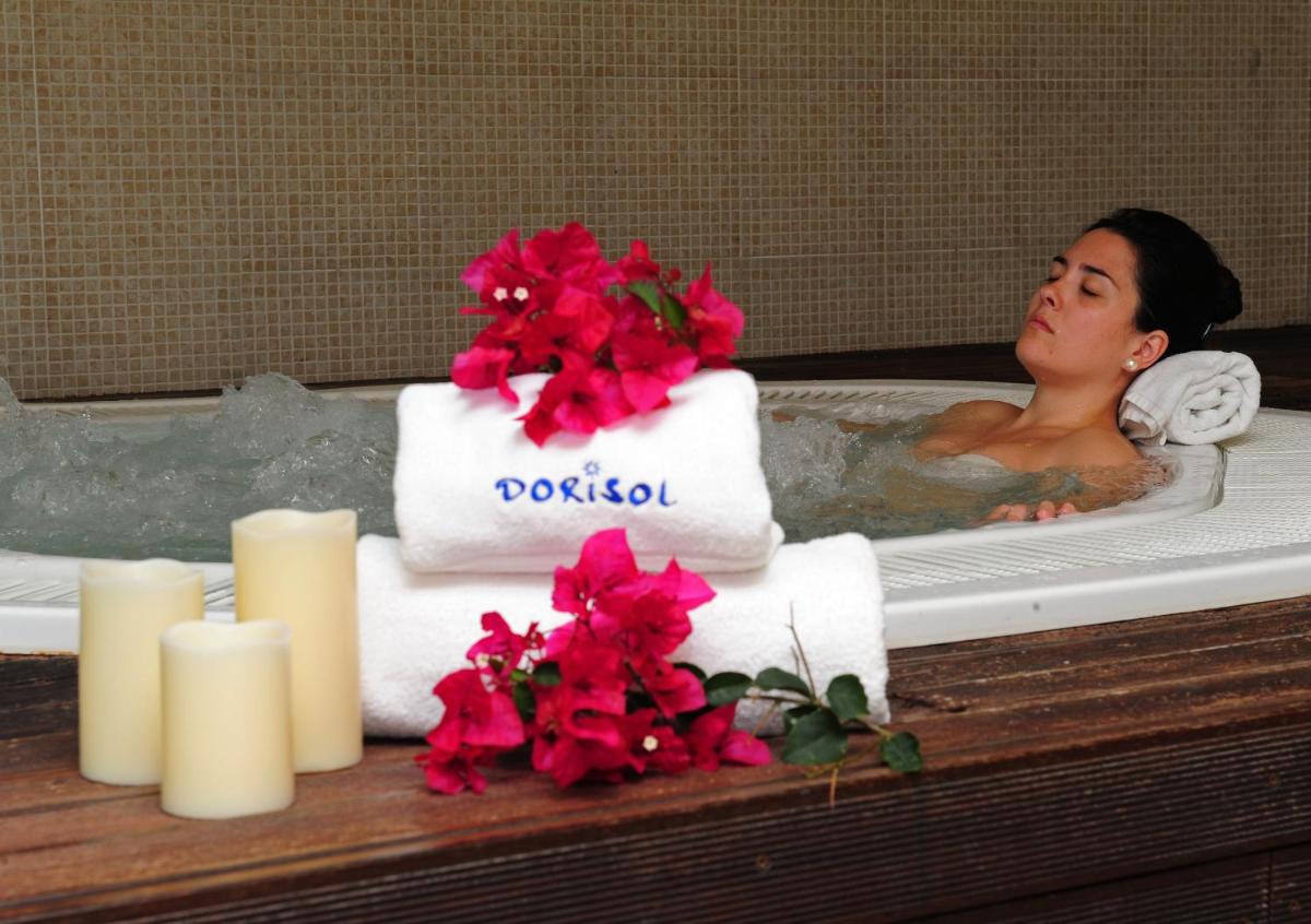 uma mulher numa banheira com toalhas e flores vermelhas em Dorisol Estrelicia Hotel no Funchal