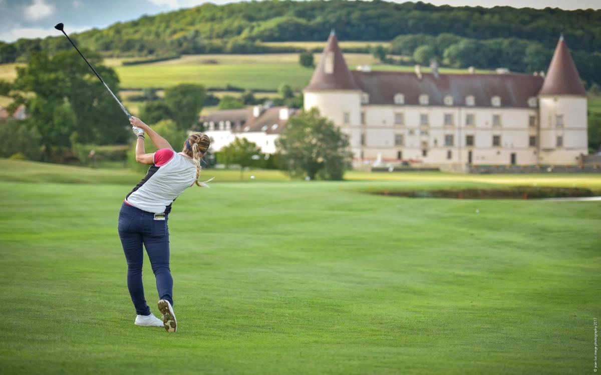 une femme faisant un swing de golf sur un parcours de golf dans l'établissement Hôtel Golf Château de Chailly, à Chailly-sur-Armançon