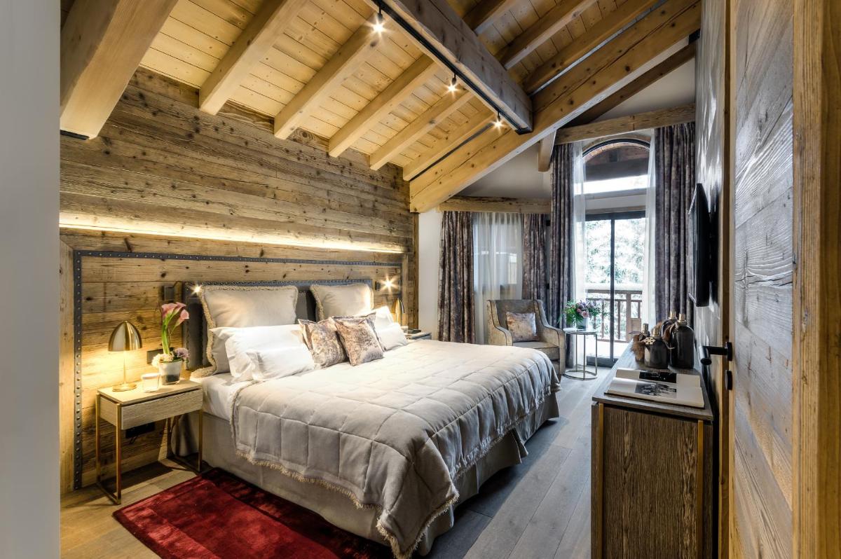- une chambre avec un grand lit et un mur en bois dans l'établissement Hôtel La Sivolière, à Courchevel 37 autres photos