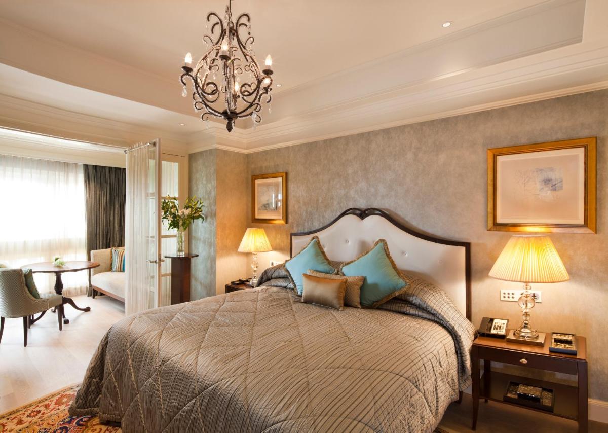 a bedroom with a large bed and a chandelier at The Taj Mahal Palace, Mumbai in Mumbai