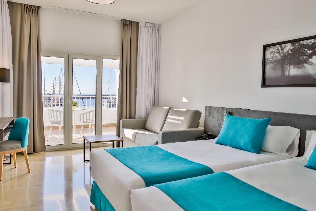 una habitación de hotel con dos camas y un sofá en Moon Hotel & SPA., en Aguadulce