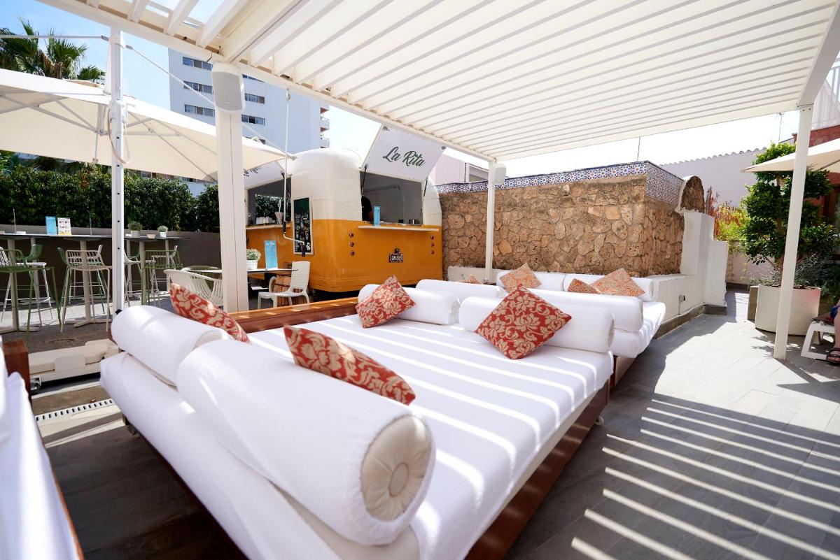 un sofá blanco sentado bajo una pérgola en un patio en Fénix Torremolinos - Adults Only Recommended, en Torremolinos