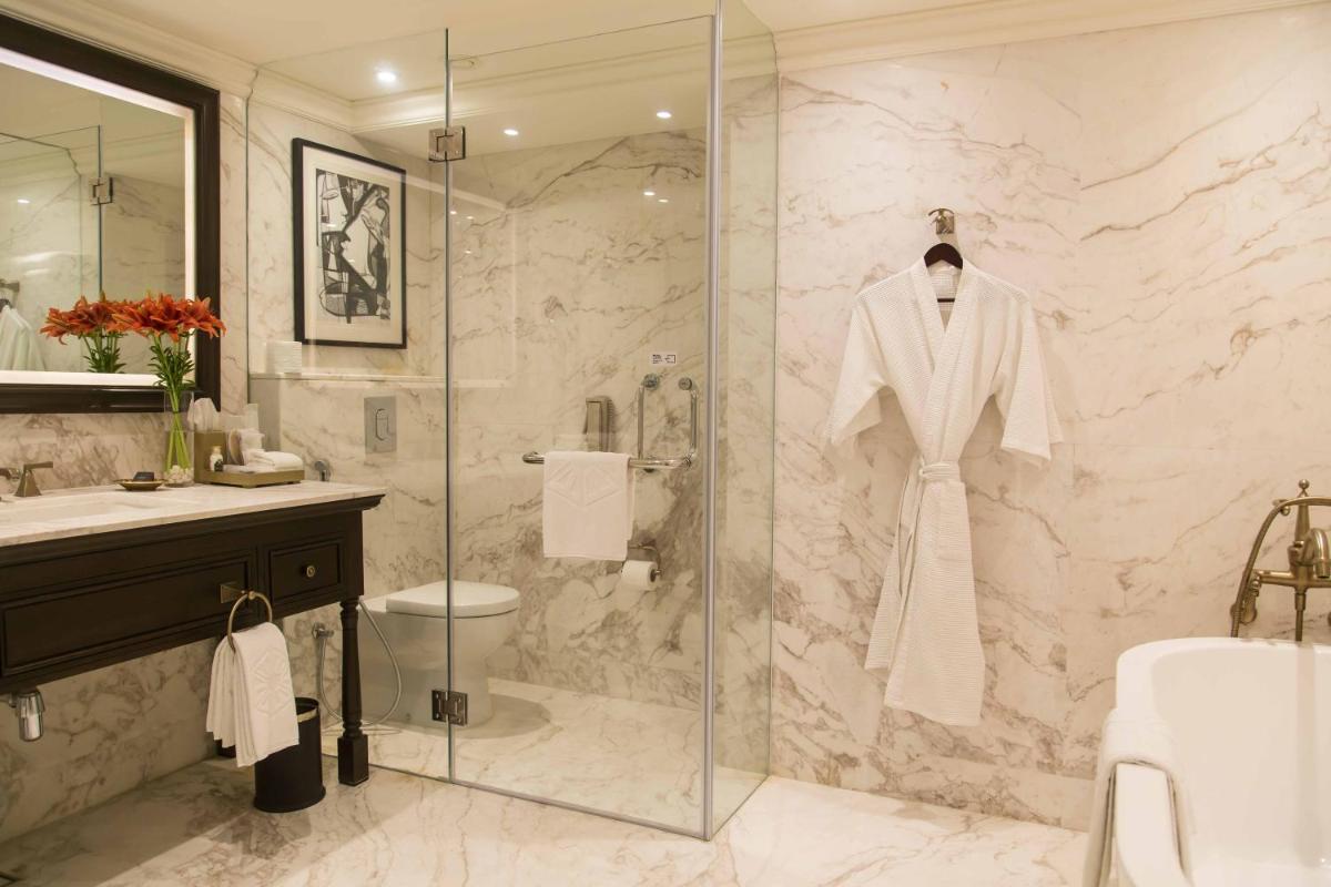 a bathroom with a shower with a white robe on a glass door at Taj Bengal in Kolkata